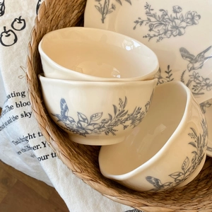 Detail of French vintage ceramic bowls with blue floral prints in a woven basket