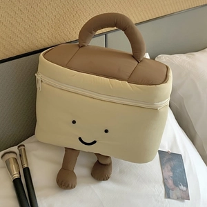 Süße Plüsch-Kosmetiktasche mit Füßen und Stickgesicht auf einem weißen Bett