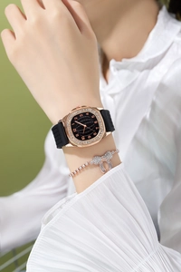 Close-up of rose gold square watch with black dial and matching rhinestone bow bracelet