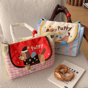 Detail view of cartoon puppy lunch bag with 3D ears and plaid patterns on soft background