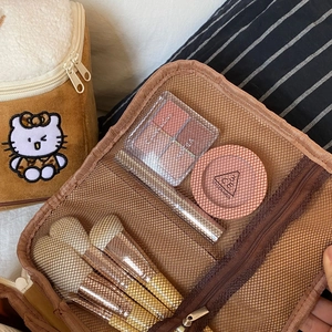 Interior detail of plush brown makeup bag with mesh pockets and brush storage slots