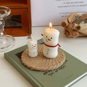 Close-up of snowman scented candles with red scarves and festive Merry Christmas flags