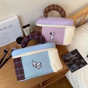 Detail of tweed and sherpa makeup bag with cute dog embroidery and plaid handle
