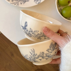 Detail of French vintage ceramic bowl with blue floral and bird prints on cream glaze