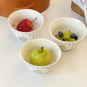 Top view of French style floral ceramic bowls with blue stripes and fresh seasonal fruits