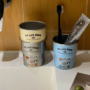 Detail of stackable stainless steel cartoon dog mugs on a bathroom sink with accessories