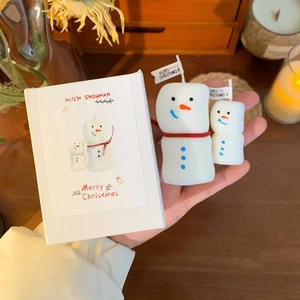 Detail of small and large snowman candles with red scarf in festive gift box packaging