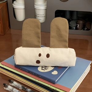 Detail view of cute canvas puppy pencil case with long brown ears on a desk