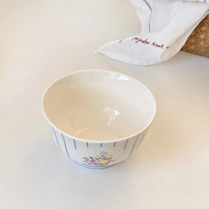 Detailed view of ceramic bowl with blue stripes and hand-painted floral pattern design