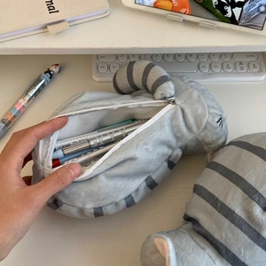 Astuccio di peluche a forma di gatto tigrato grigio su scrivania bianca con cancelleria