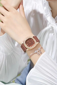 Close-up of rose gold rhinestone watch with brown strap and matching crystal bracelet