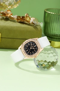 Detail of luxury rhinestone square quartz watch with white silicone strap on green velvet