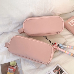Close-up of pink canvas stationery bags with handles on a minimalist white desk