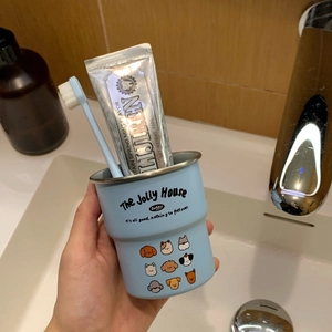 Detail of cute cartoon dog mouthwash cup with metal rim holding toothbrush and toothpaste