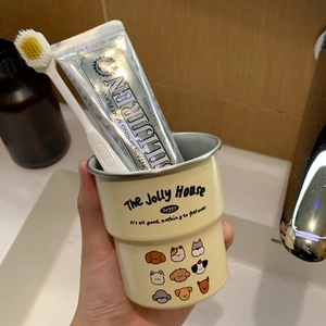 Close-up of yellow cartoon puppy mouthwash cup held in hand in a bathroom setting