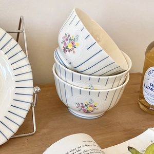 Close-up of vintage ceramic bowls with blue stripes and floral patterns on wooden table