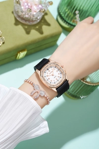 Detail of rose gold rhinestone watch with black silicone strap and a bow bracelet