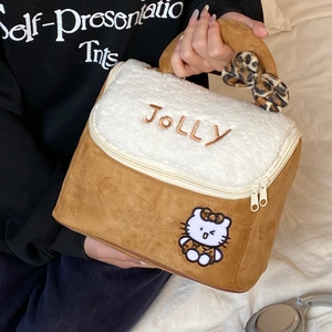 Cute brown plush makeup bag with Jolly embroidery and Kitty patch held by a person