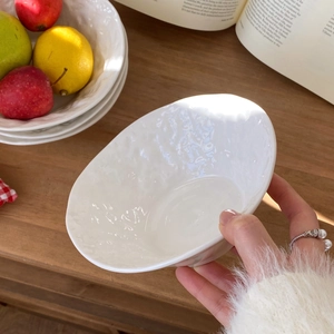 Detailed view of hand-held white ceramic bowl with natural rock texture on wooden desk