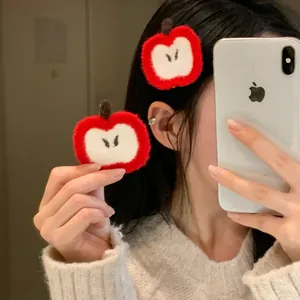 Close-up of red apple felt hair clip showing handmade texture and embroidery detail