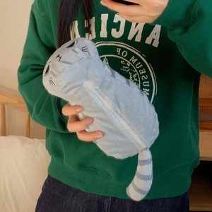 Dettaglio dell'astuccio in peluche a forma di gatto grigio con coda a strisce