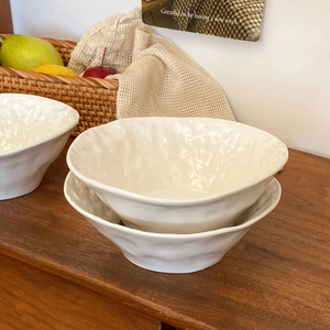 Detail of white ceramic bowls with rock-like hammered texture on a rustic wooden table