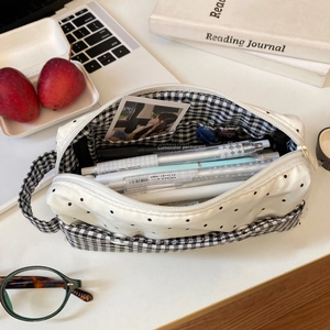 Vue détaillée d'une trousse blanche à pois avec doublure à carreaux pour fournitures