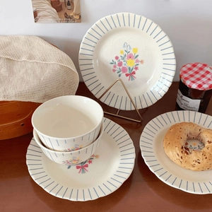 Close-up of vintage ceramic bowl with blue stripes and floral pattern on a wooden table