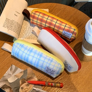 Close-up of checkerboard pattern canvas pencil cases with carry handles on wooden desk