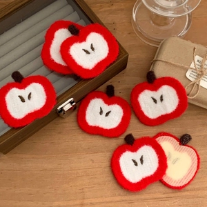 Macro shot of cute embroidered apple hair stickers on a warm wooden surface