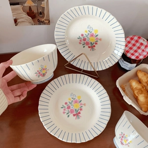 Close-up of French vintage ceramic bowl set with floral patterns and blue stripes