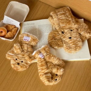 Detail of plush tiger-striped mittens with dog face design and brand label on a book