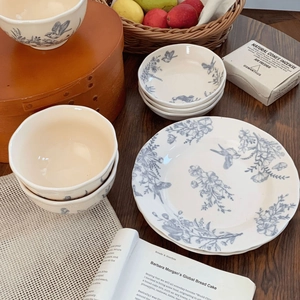 French vintage ceramic dinnerware set with blue floral and bird patterns on wooden table
