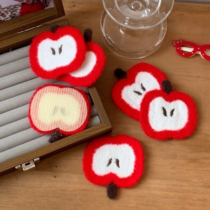 Cute red and white knitted apple hair clip accessory on a rustic wooden jewelry box