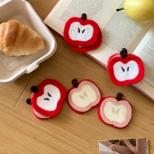 Close-up of cute red apple felt hair pads and stationery on a rustic wooden desk