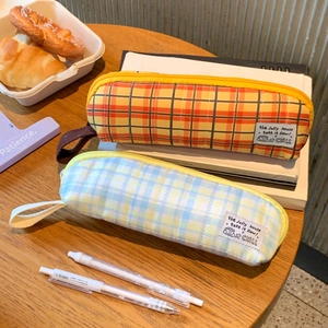 Detail of quilted plaid pencil cases with fabric handles in vibrant orange and soft blue
