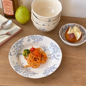French vintage ceramic dinnerware set with blue floral bird patterns on a wooden table