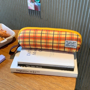 Detail of yellow plaid canvas pencil case with a zipper and portable brown handle strap