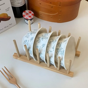 Rustic wooden dish rack holding four ceramic bowls with blue floral relief patterns