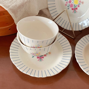 Detail of vintage floral ceramic bowl with pink bow and blue stripes on wooden table