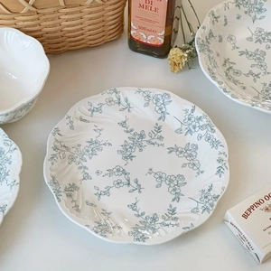 Detail of French vintage ceramic plate featuring blue floral embossing and wavy edges