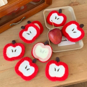 Close-up of cute red apple hair clips with detailed embroidery on a wooden table