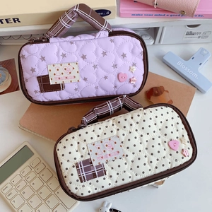 Quilted pencil case detail with heart stitching, plush buttons and portable plaid handle