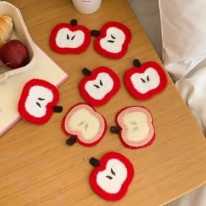 Close-up of 8 handmade red apple crochet patches on a natural wooden background