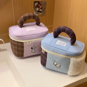 Detail of quilted cosmetic bag with cartoon dog embroidery and checkered top handle