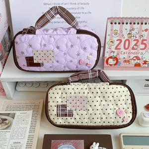Detail of quilted pencil cases with heart patterns and handles for stationery storage