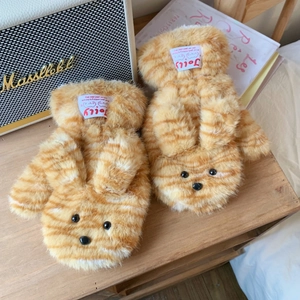 Detail of plush orange tiger stripe mittens featuring cute rabbit ears on a wooden desk