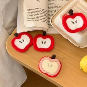 Detail view of cute red apple felt patches on a wooden table with vintage books