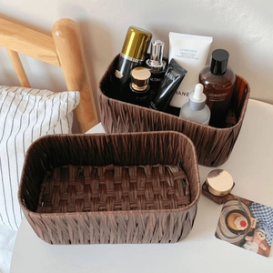 Macro view of two dark brown woven storage baskets with detailed wicker texture on a nightstand