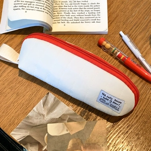 Close-up of quilted fabric pencil case with red zipper on a minimalist wooden desk